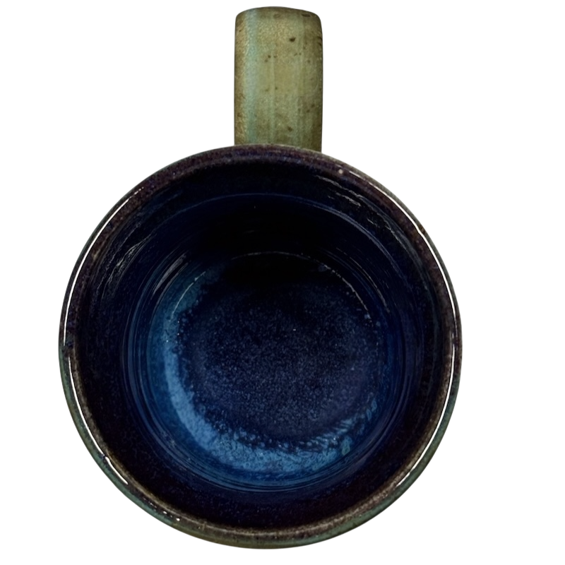 Top view of vintage Caffe Pergolesi mug with blue interior and rustic handle on black background
