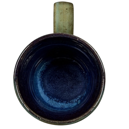 Top view of vintage Caffe Pergolesi mug with blue interior and rustic handle on black background